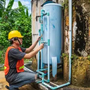 A technician checks outdoor piping for mechanical seal failure in a rural water pump system