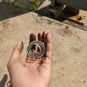 Greasy hand displays a deformed spring removed due to mechanical seal failure in a pump
